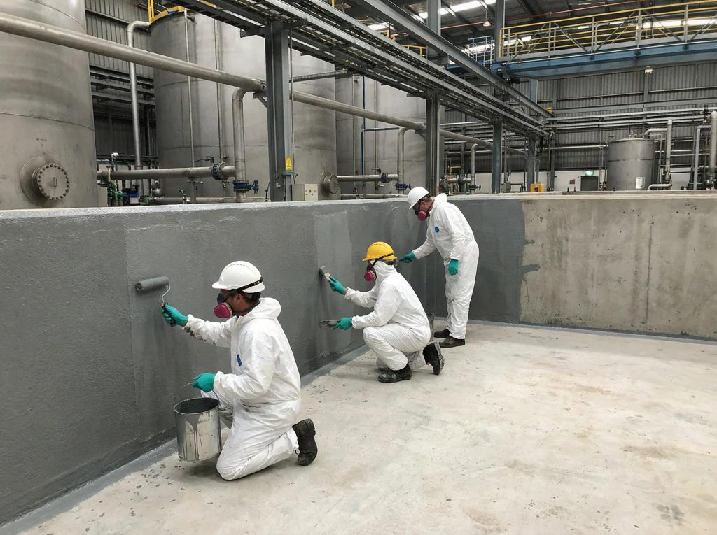 Workers coating an industrial bund wall